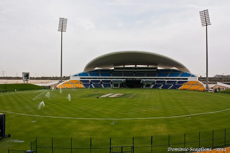 Zayed Cricket Stadium with its curved roof, floodlights and green outfield